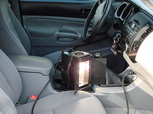 Mobile video lighting unit being recharged on location, plugged into a car's cigarette lighter or power port.